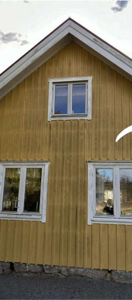 Gul träfasad med grå beläggning före rengöring